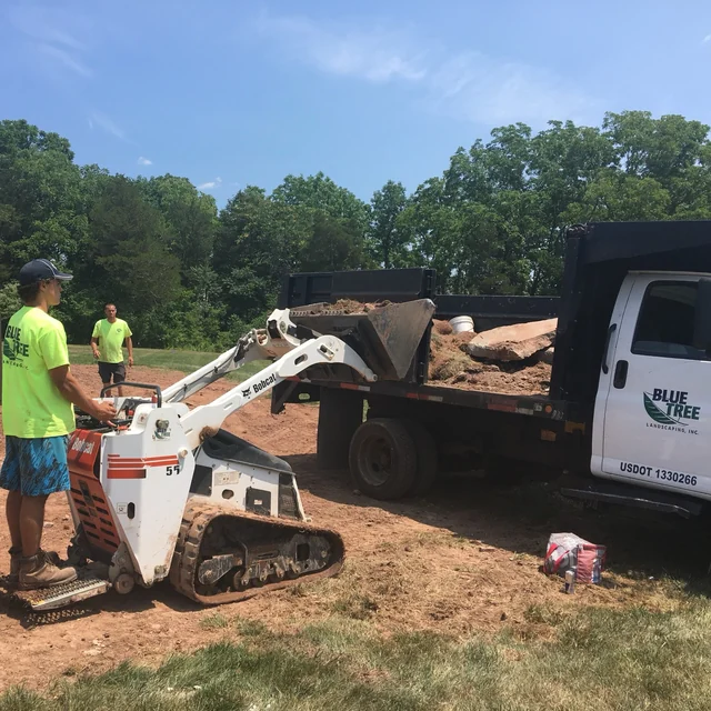 Blue Tree crew members beside a compact loader.