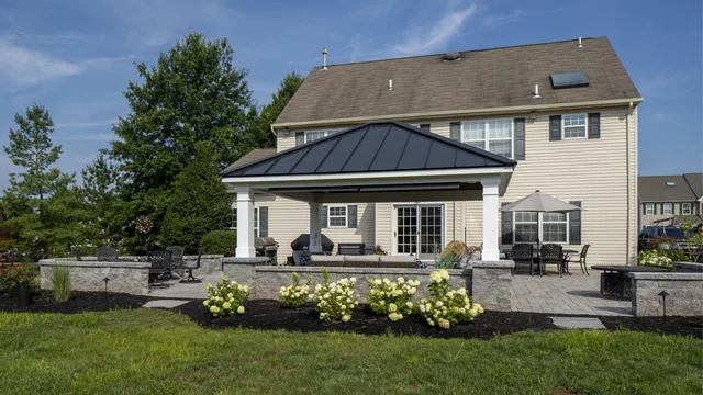 Blue Tree outdoor living project in Skippack Township with a covered patio, stone sitting walls and flowering planting beds.