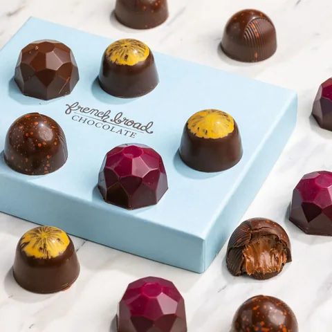 French Broad Chocolates bonbons arranged on the signature blue gift box, with one cut open to show the centre.